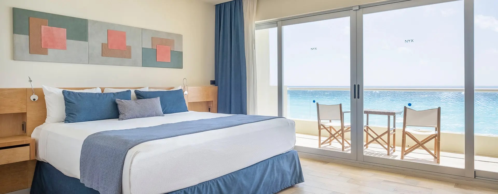 Contemporary guest room at Hotel NYX Cancun featuring two comfortable beds, a desk for business use, and a private balcony with ocean views. High-quality accommodations suitable for MICE event attendees, corporate group bookings, and incentive travel programs in the Cancun Hotel Zone.