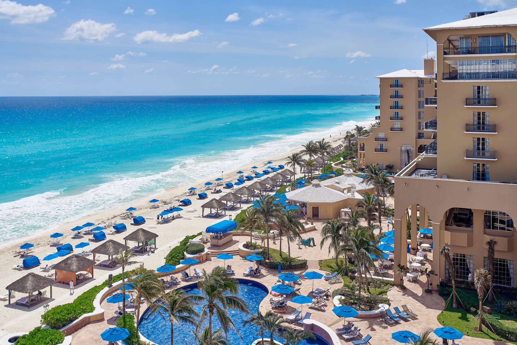 High-angle view of the Kempinski Hotel Cancún pool area and white sand beach, showcasing luxury outdoor networking spaces for corporate groups, incentive travel programs, and beachfront gala dinners in Mexico.