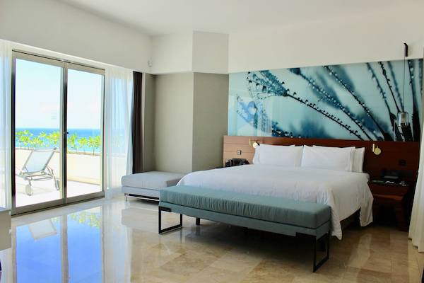 Interior of a modern premium king bedroom at Live Aqua Beach Resort Cancun, featuring a private sun terrace with ocean views, minimalist design, and luxury amenities for VIP corporate guests and high-performance incentive travel winners