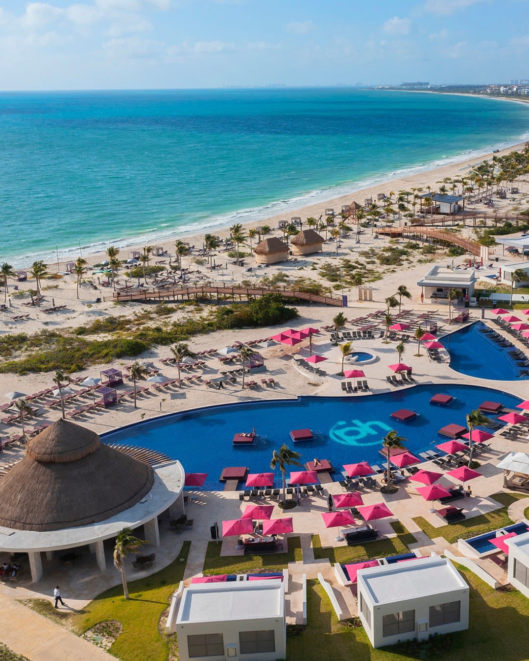 High-angle shot of the luxury pool area and beach club at Planet Hollywood Adult Scene Cancun, featuring pink umbrellas and lounge areas suitable for corporate networking, team-building activities, and luxury incentive rewards.