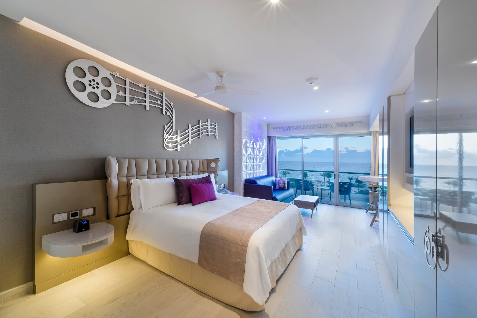 Interior of a luxury guest suite at Planet Hollywood Adult Scene Cancun with modern cinema-themed decor and an ocean-view balcony, perfect for housing VIP corporate guests and executive conference attendees.