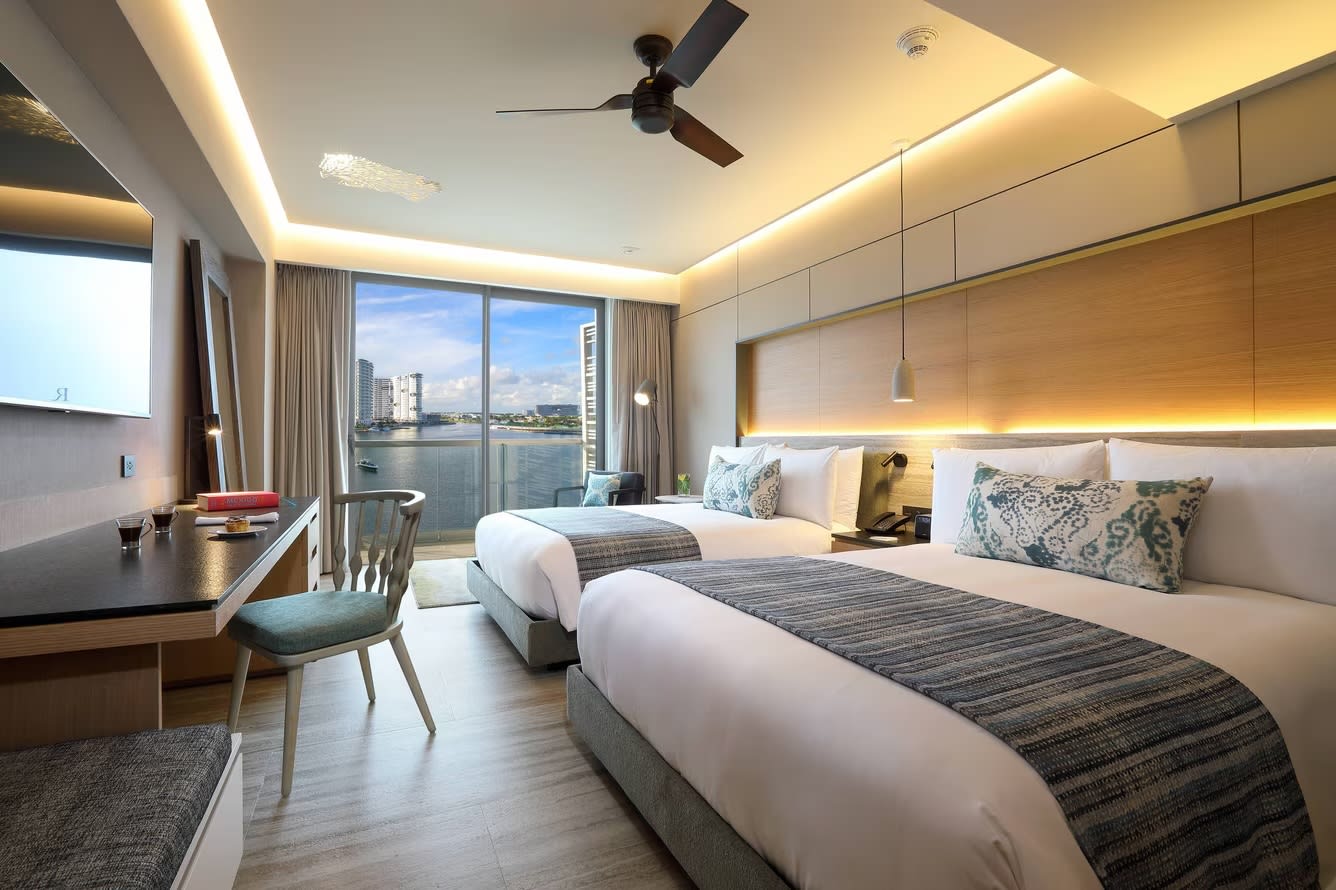 Luxury guest room at Renaissance Cancun Resort & Marina with two queen beds, a dedicated workstation, and a private balcony overlooking the marina. Ideal accommodation for MICE delegates and corporate incentive travel programs requiring premium comfort and high-speed connectivity.
