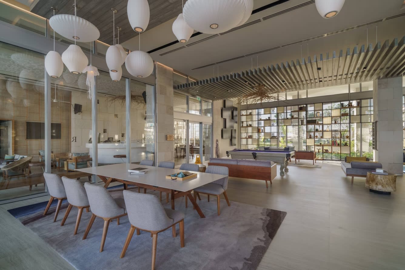 Modern and stylish lobby at Renaissance Cancun Resort & Marina, showcasing a versatile coworking space and networking area. The interior features a large conference table, contemporary lighting, and a billiard table, ideal for corporate break-out sessions, informal business meetings, and incentive group social gatherings in a professional, upscale setting.
