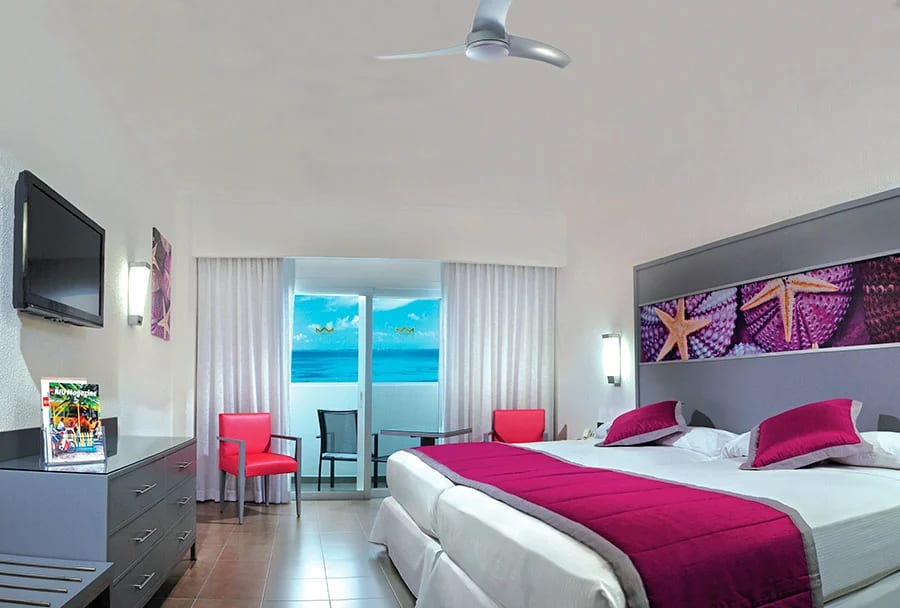 Modern oceanfront guest room at Hotel Riu Cancun featuring a private balcony, ergonomic layout, and high-end amenities suitable for corporate delegates and incentive travel group housing in Cancun.