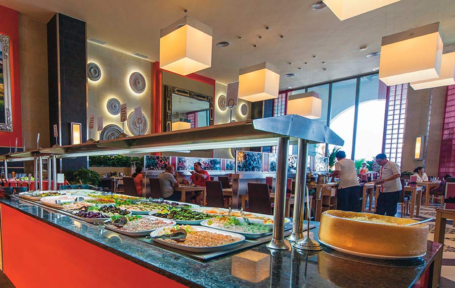 Spacious buffet dining area at Riu Cancun with modern lighting, showing high-capacity seating and diverse culinary options for corporate group breakfasts and MICE event catering.