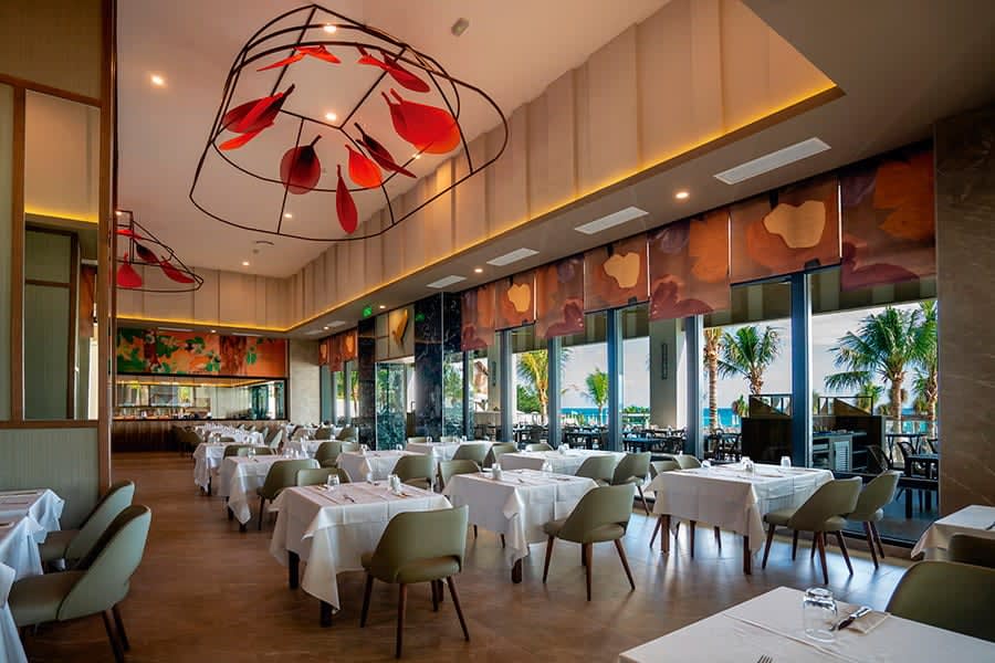 Modern semi-outdoor lounge at Riu Palace Kukulkan in Cancun, featuring stylish wicker seating and a stage area. An ideal setting for MICE industry networking events, corporate breakout sessions, and luxury incentive travel groups overlooking the Caribbean.