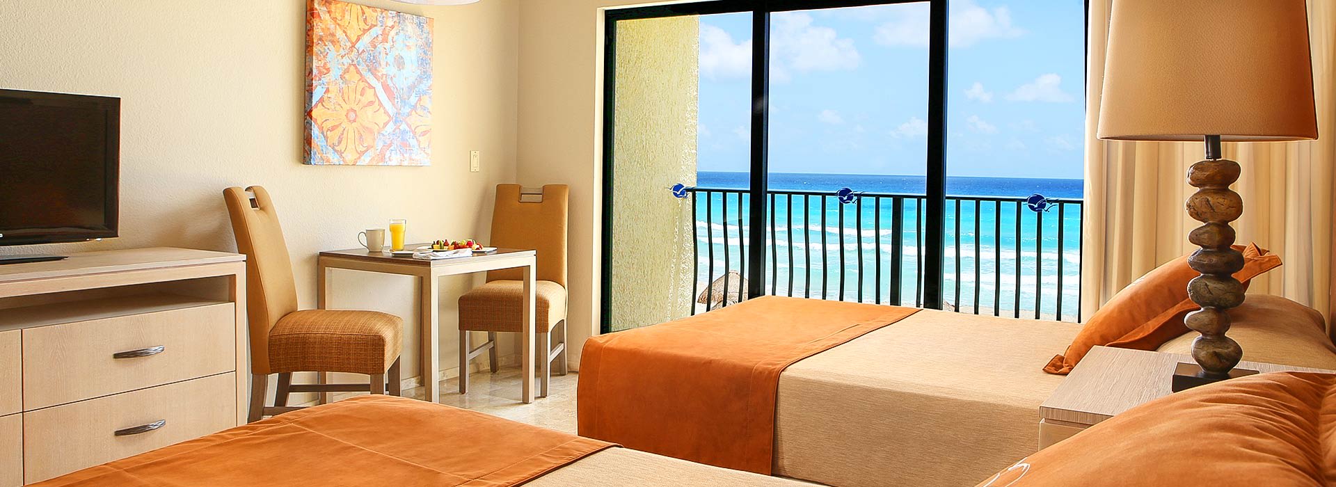 Oceanfront hotel room at Royal Sands featuring twin beds, a private balcony with sea view, in-room breakfast setup, and workspace ideal for MICE travelers seeking comfort and convenience.