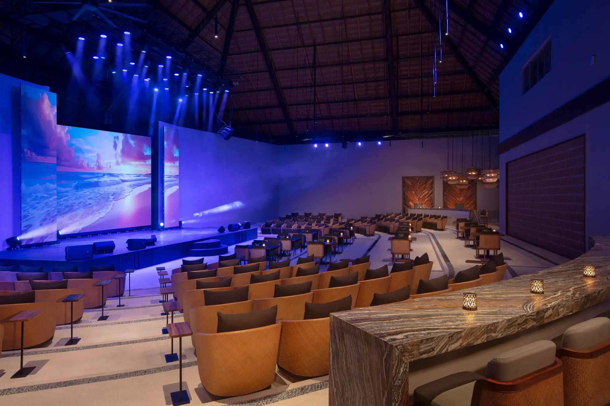 Modern auditorium at Secrets Playa Blanca Costa Mujeres featuring cushioned seating, individual tables, digital screens, and ambient lighting—ideal for MICE conferences, executive presentations, and corporate sessions in Mexico.