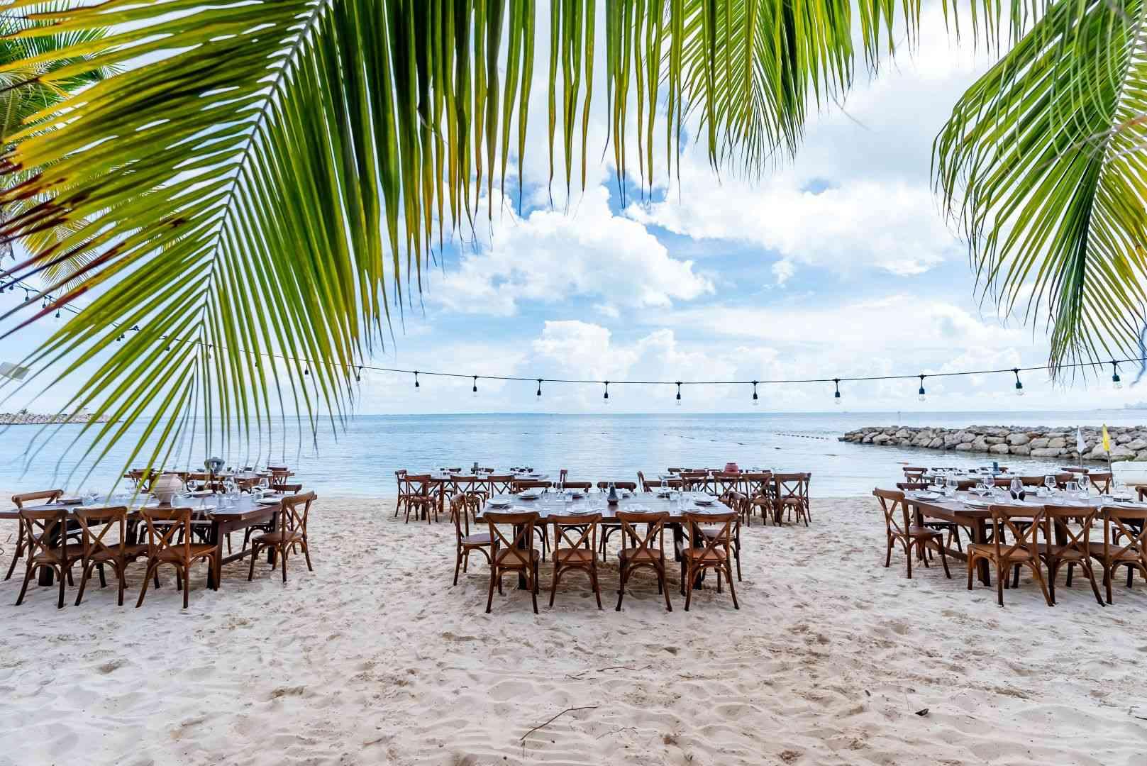 Elegant beachside dining setup at SLS Cancun with wooden tables, string lights, and ocean views—ideal for MICE welcome receptions, incentive dinners, and corporate celebrations in a tropical setting.