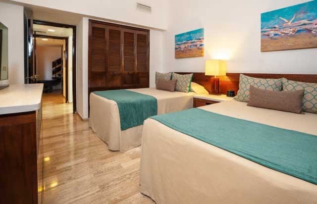 Double guestroom at The Royal Cancun featuring teal accents, beach-themed artwork, and modern amenities—ideal for MICE group stays, incentive travel, and corporate accommodations in Mexico.