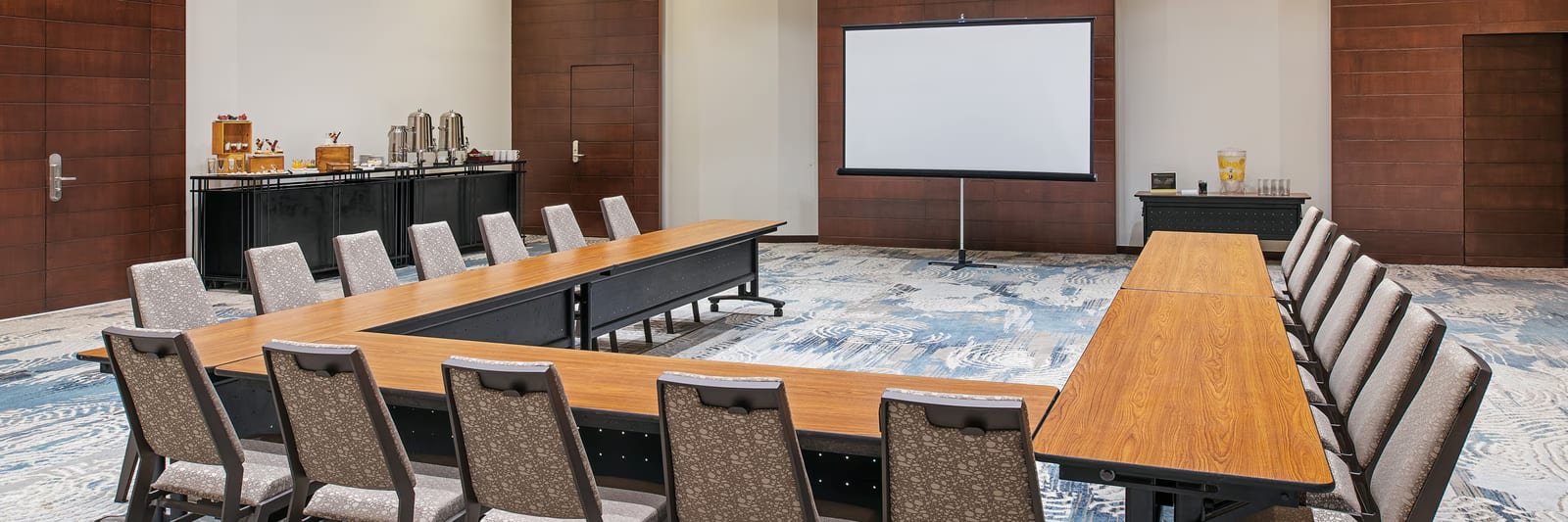 A professional indoor meeting room at The Westin Cancun Resort & Spa featuring a U-shape table configuration and ergonomic seating. The setup includes a projector screen for corporate presentations, a dedicated coffee break and catering station, and modern decor, making it an ideal venue for executive board meetings, workshops, and MICE industry seminars.