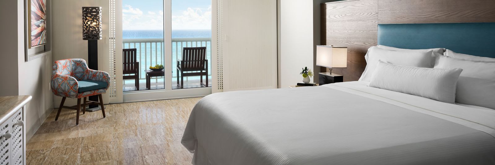Luxurious ocean-front guest room at The Westin Cancun Resort & Spa, ideal for corporate incentive travel. The room features a signature plush bed, a private balcony with Caribbean Sea views and outdoor seating, and a modern work area, providing a premium stay for conference attendees and MICE group delegates.