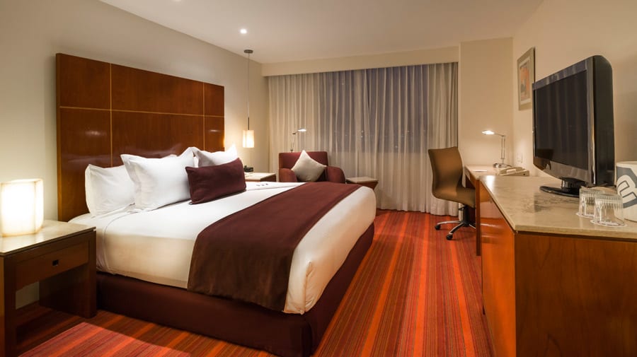 Luxury King Bedroom at Camino Real Aeropuerto México featuring an ergonomic workstation, high-speed internet access, and premium bedding for MICE delegates and corporate travelers at AICM.