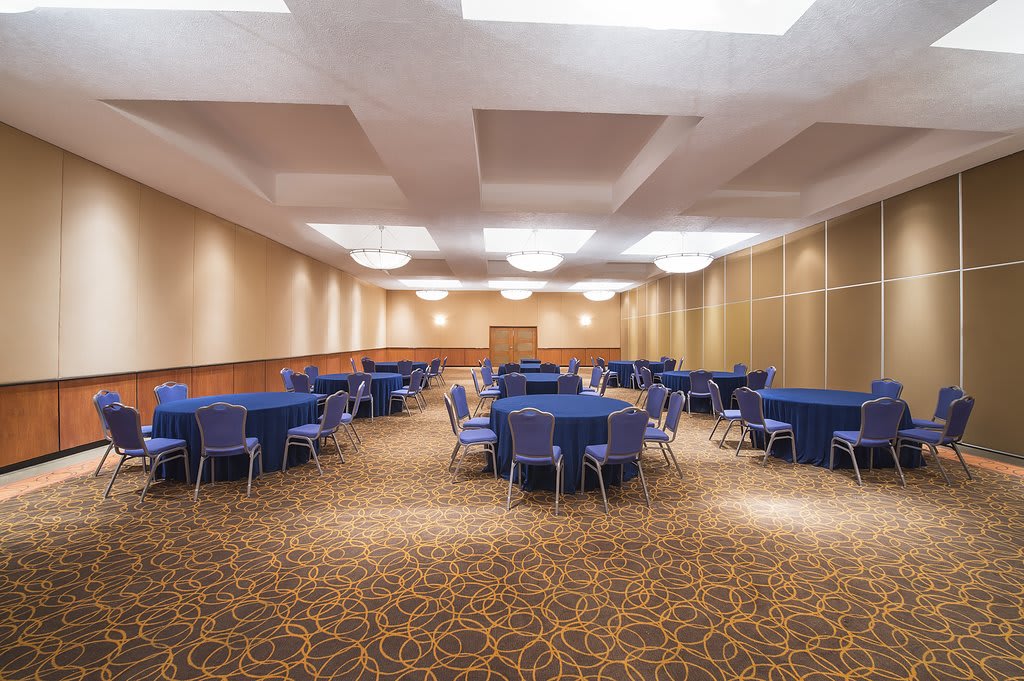 Spacious meeting room at Fiesta Americana Reforma in Mexico City, featuring round tables with blue linens, cushioned chairs, and modern lighting. Ideal for MICE events including seminars, corporate gatherings, and incentive receptions