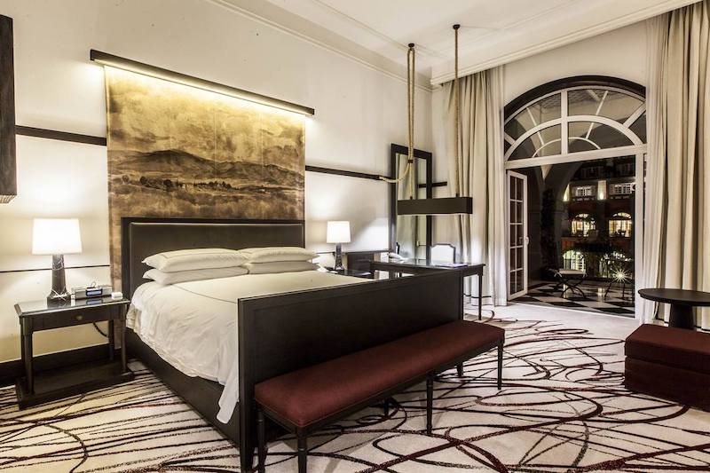 Elegant guest room at Four Seasons Hotel Mexico City featuring a large bed, illuminated mural, desk, and balcony view. Ideal for MICE travelers seeking upscale accommodations with work-friendly amenities and refined ambiance