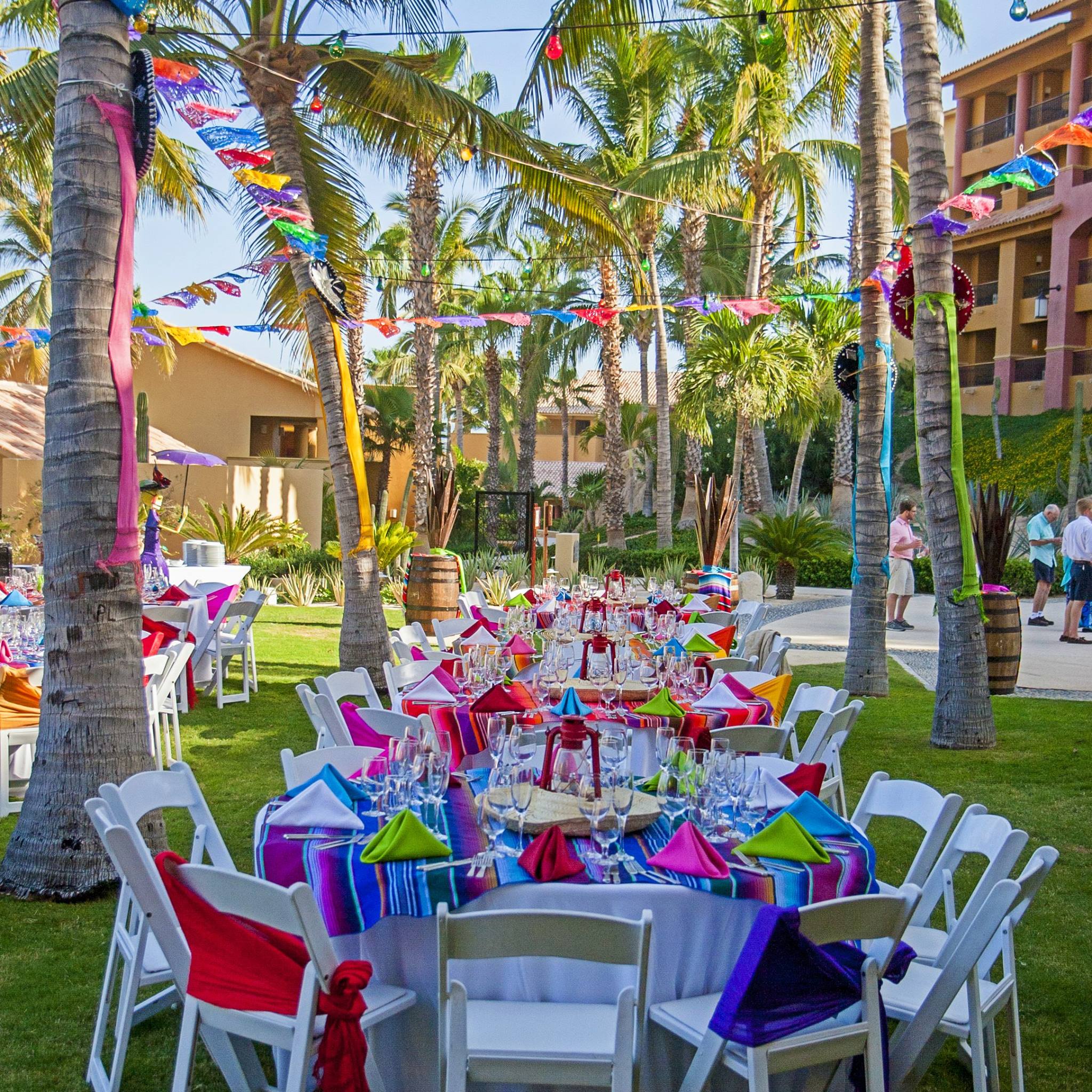 Vibrant outdoor event at Grand Fiesta Americana Los Cabos All Inclusive Golf & Spa featuring colorful table settings, papel picado banners, and tropical ambiance—ideal for MICE celebrations, cultural welcome receptions, and incentive group gatherings in Baja California Sur.