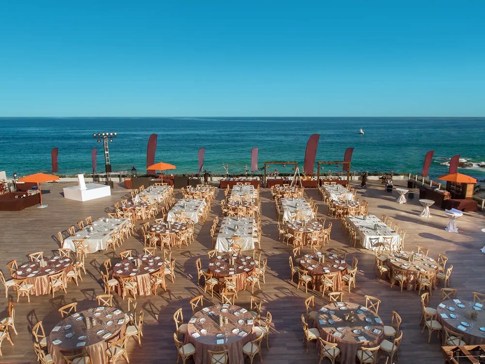 Oceanfront deck event setup at Grand Velas Los Cabos featuring dining tables, cocktail stations, and branding flags—ideal for MICE welcome receptions, incentive gatherings, and corporate celebrations in Baja California Sur.