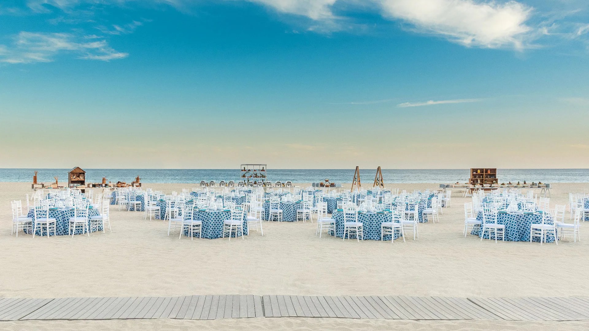 Beachside event setup at Hyatt Ziva Los Cabos featuring round tables with blue linens, white chairs, and ocean backdrop—ideal for MICE banquets, incentive dinners, and corporate celebrations in Baja California Sur.