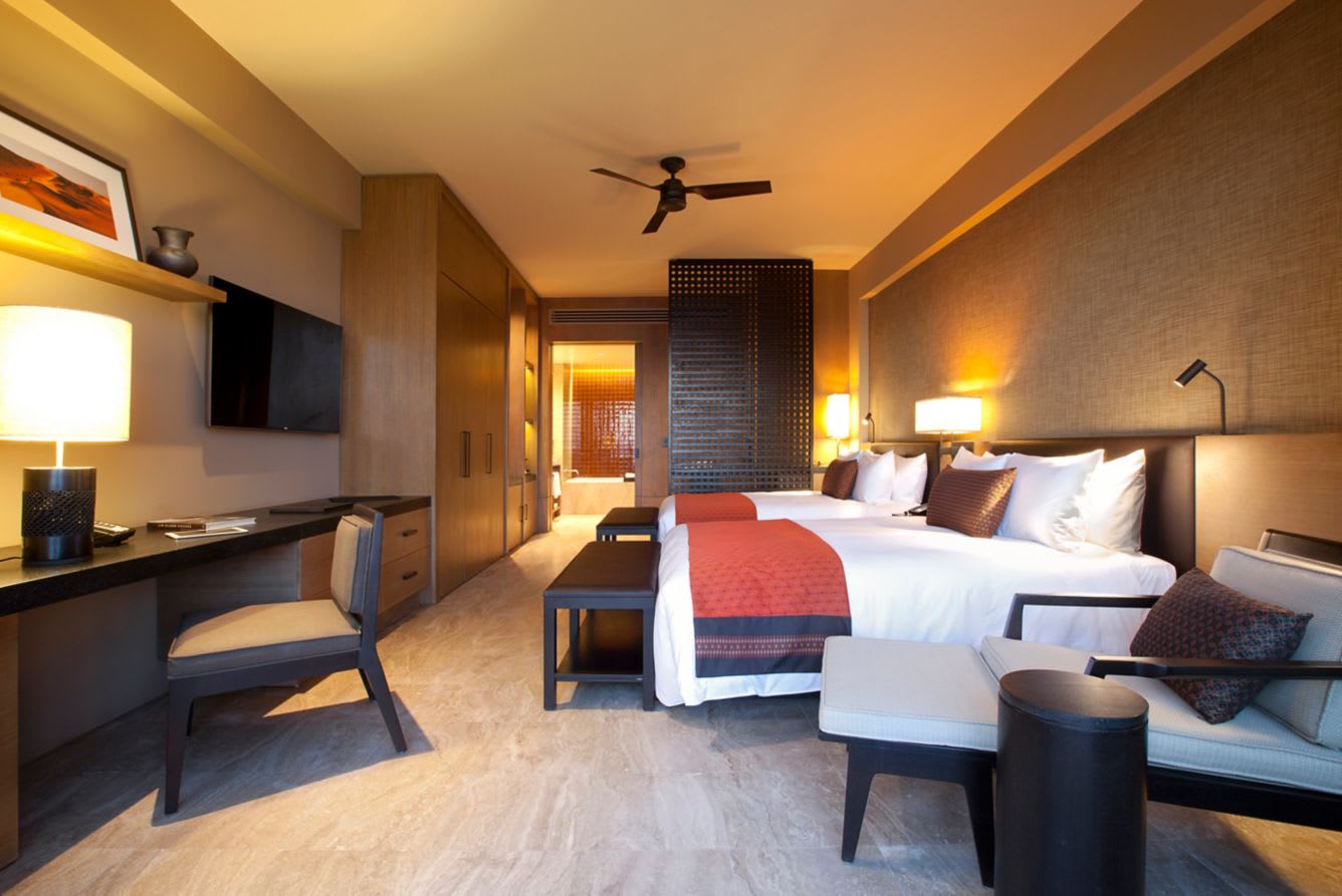 Contemporary double-bed room at JW Marriott Los Cabos Beach Resort & Spa featuring wood accents, work desk, and open bath—ideal for MICE group stays, incentive travel, and executive accommodations in Baja California Sur.