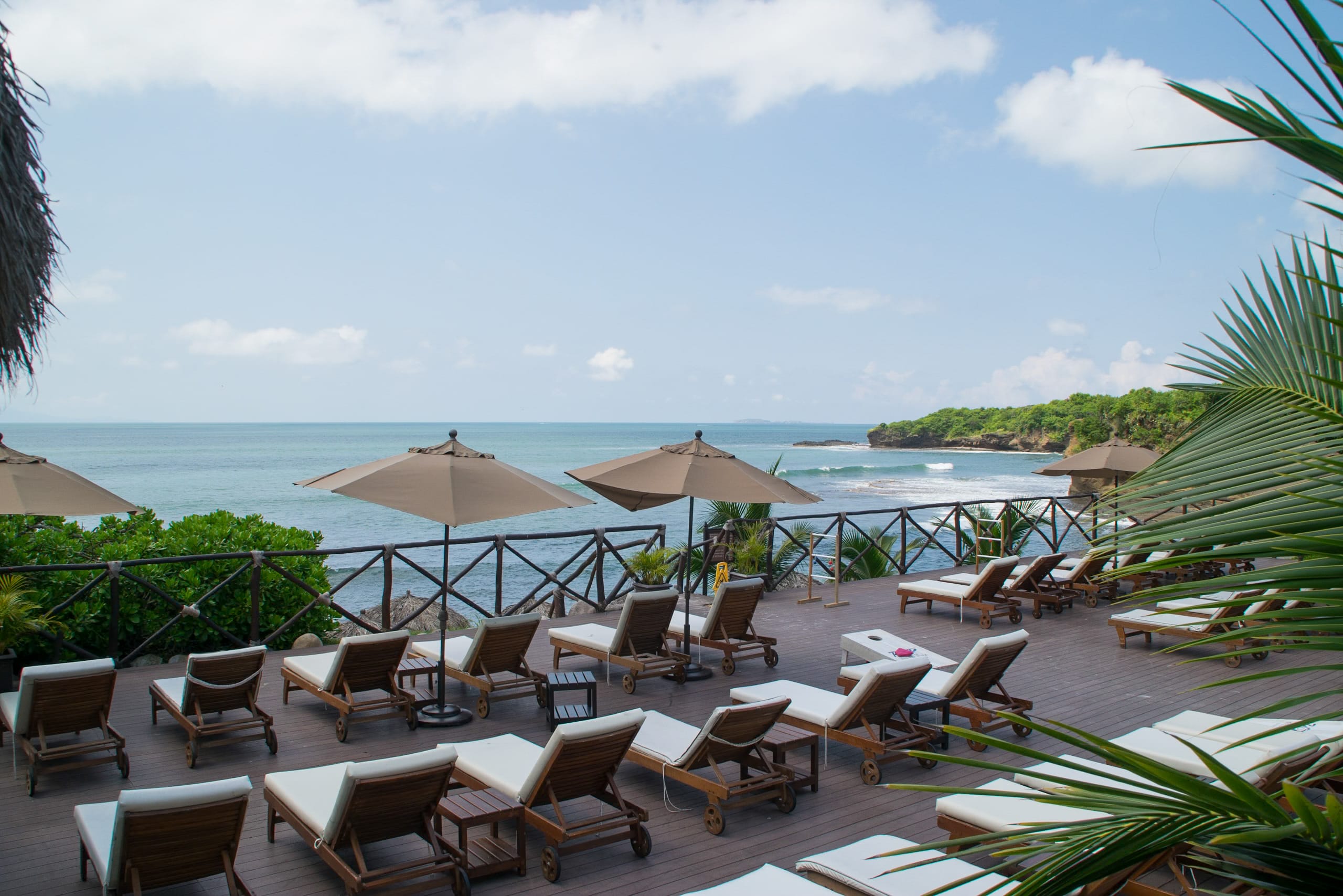 Oceanfront pool terrace at a luxury Riviera Nayarit hotel, featuring wooden sun loungers, umbrellas, and sweeping Pacific ocean views, ideal for private MICE cocktail receptions, incentive group buyouts, and executive events