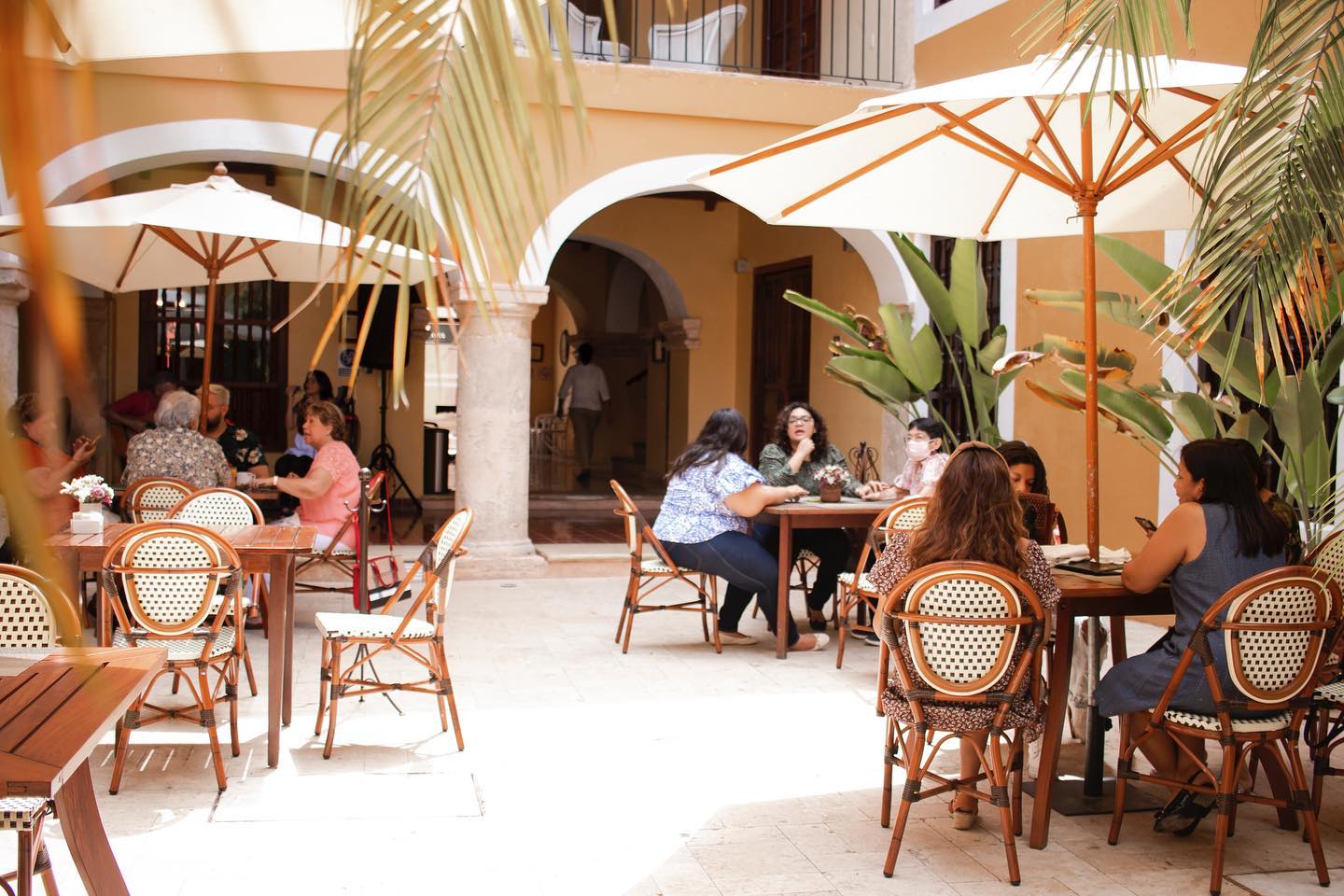 Serene view through a rustic stone archway at Hotel Boutique Casa Don Gustavo in Campeche, Mexico, overlooking a turquoise pool with reflections, leading to a historic courtyard with plants—exclusive MICE retreat for incentive travel wellness, corporate meetings, conferences, and group exhibitions in a UNESCO colonial setting.