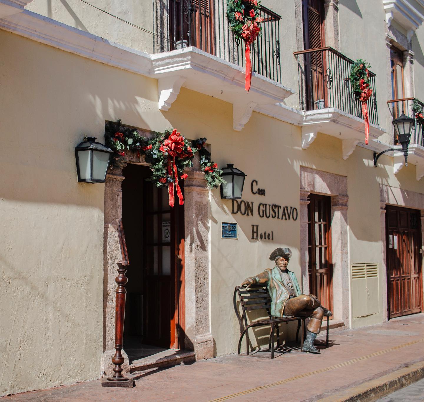Twilight poolside courtyard at Hotel Boutique Casa Don Gustavo in Campeche, Mexico, with a elegantly set dinner table on lush grass, flickering torches, stone stairs, lounge chairs with towels, and warm-lit colonial walls—premier MICE destination for incentive travel rewards, corporate meetings, conferences, and exclusive group exhibitions in a UNESCO World Heritage site.