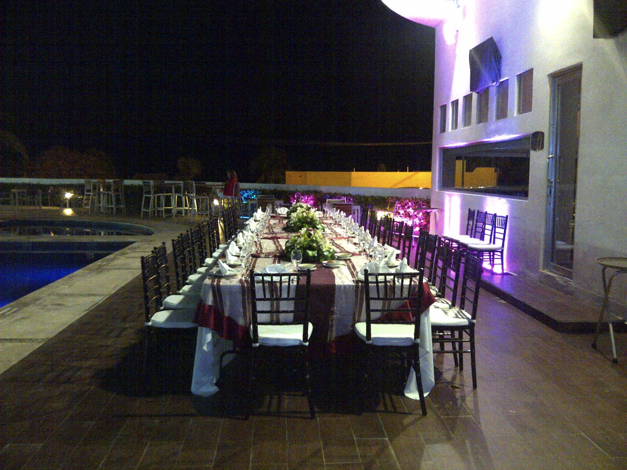 Elegant outdoor group dinner setup by the pool at Holiday Inn Campeche, featuring a long banquet table with formal décor, ideal for corporate events, incentive programs, and MICE gatherings in Mexico