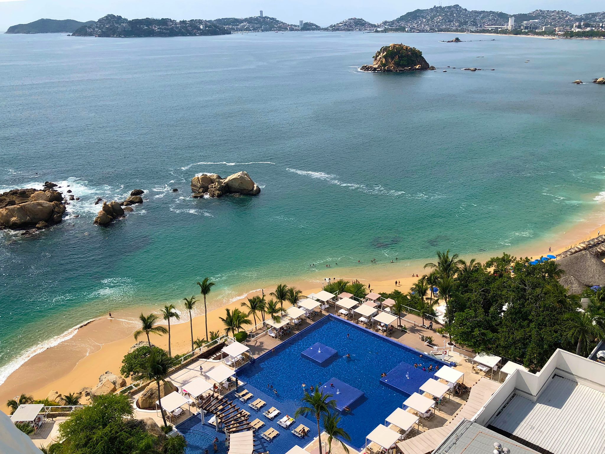 Spacious beachfront resort with large rectangular pool, lounge areas and umbrellas adjacent to sandy beach and turquoise ocean; ideal for MICE groups, corporate meetings, incentive travel and beachfront networking events.