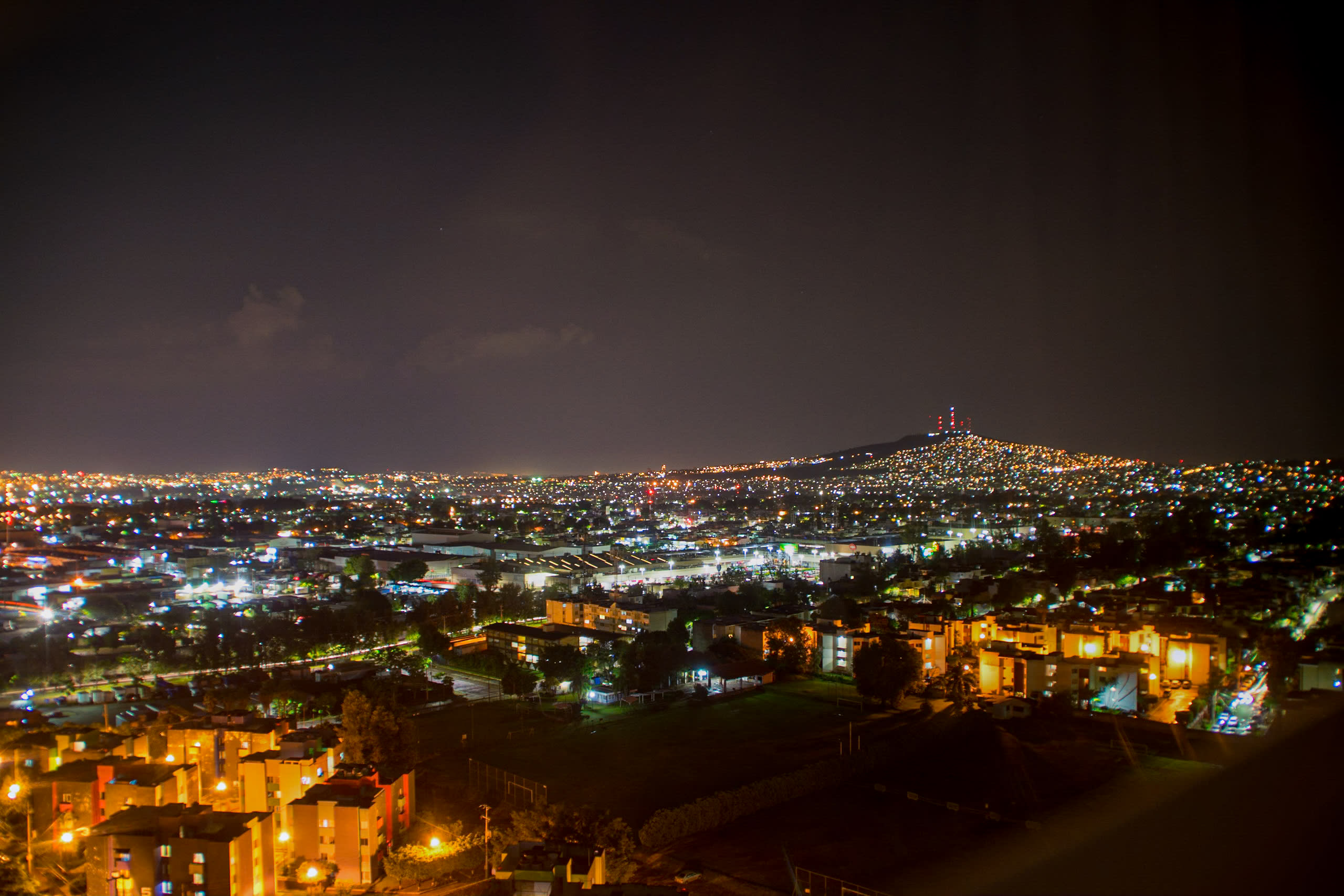 A breathtaking panoramic night view of the Guadalajara city skyline, with city lights stretching to the horizon and illuminating the hills. This dynamic image highlights the city’s vibrant nightlife and appeal for evening MICE events, rooftop receptions, and celebratory dinners for incentive travel groups.