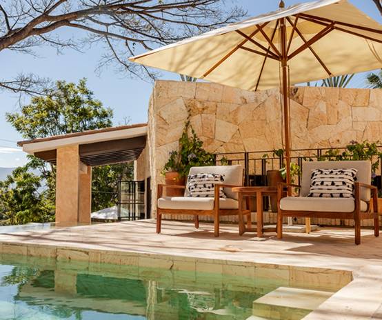 Tranquil poolside patio in Oaxaca with cushioned seating, stone wall, and umbrella—ideal for MICE incentive travel, wellness breaks, and informal networking.