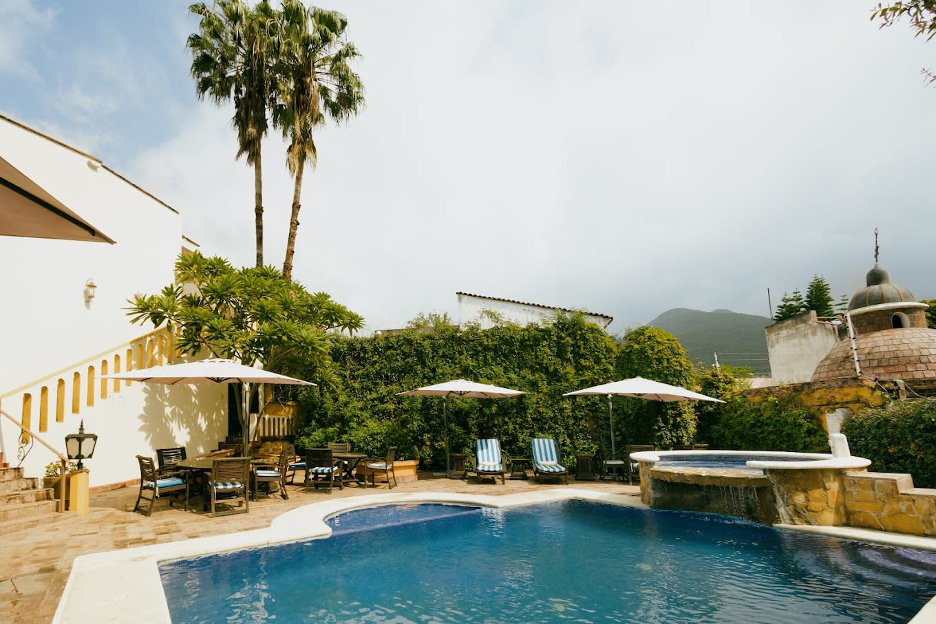 Serene poolside area at Hotel Hacienda Los Laureles Spa in Oaxaca with lounge chairs, umbrellas, and mountain views—ideal for MICE incentive travel and wellness retreats.