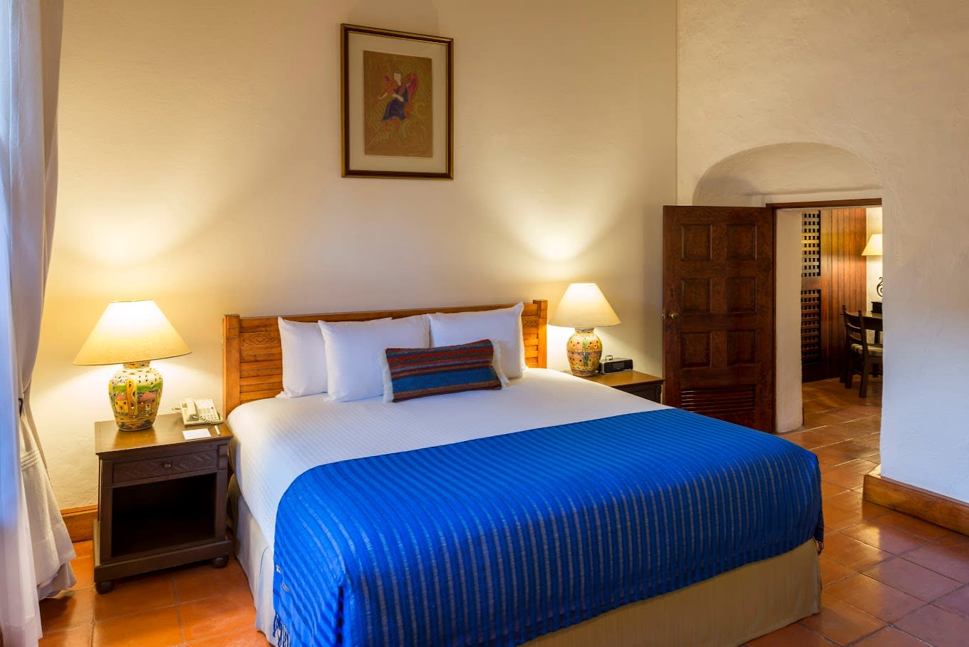 Elegant guest room at Hotel Quinta Real Oaxaca with blue bedspread, ceramic lamps, and warm lighting—ideal for MICE attendees seeking comfort and colonial charm.