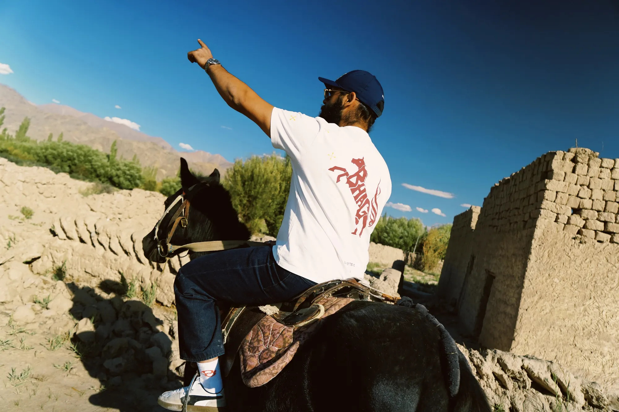Wild Strides Tee in Ivory, back print, worn on horseback in Ladakh