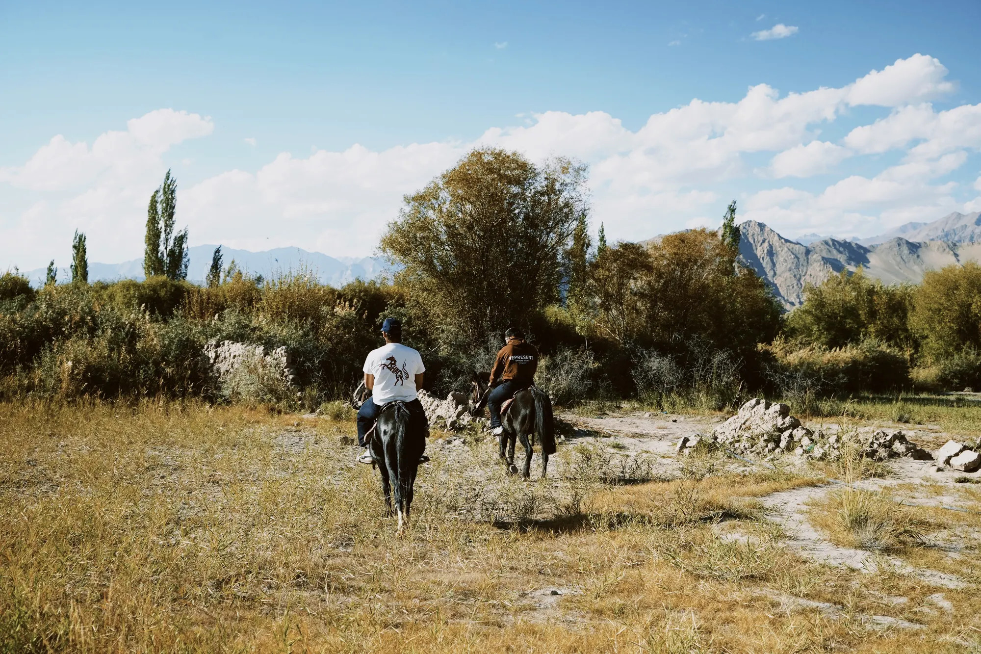 Two riders out on the trail in Ladakh, one in the Wild Strides Tee