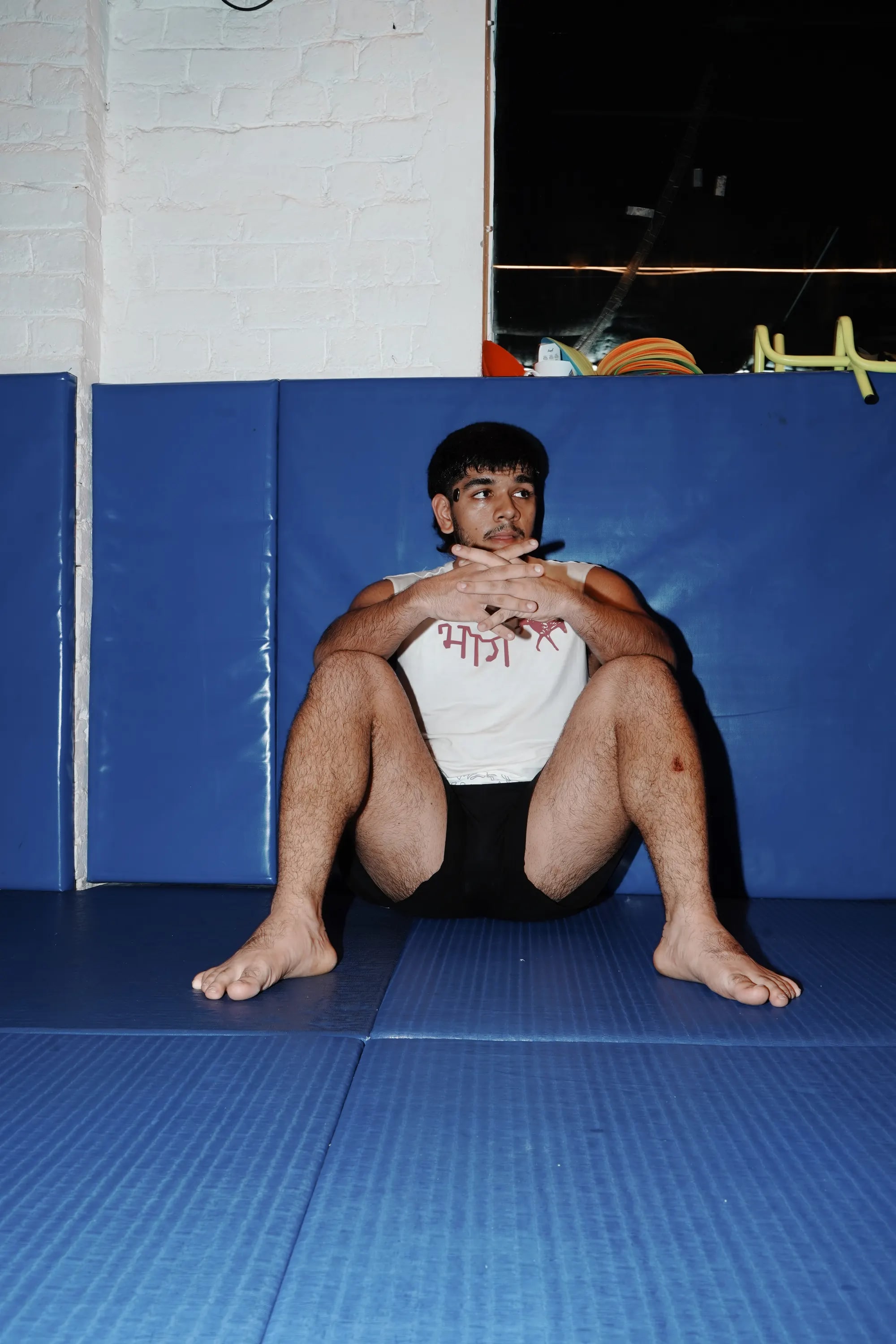 भाग Muscle Tank in Bone, worn loose, seated on the mats