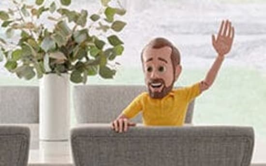 Child sitting at a wooden dining table with gray upholstered chairs, raising one hand, next to a white vase with green foliage.