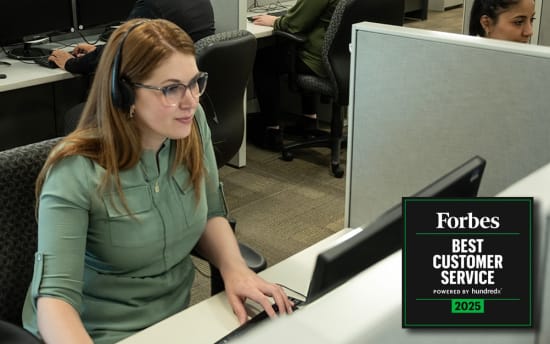 Woman wearing a headset working at a computer in an office cubicle with a Forbes Best Customer Service 2025 award badge displayed.