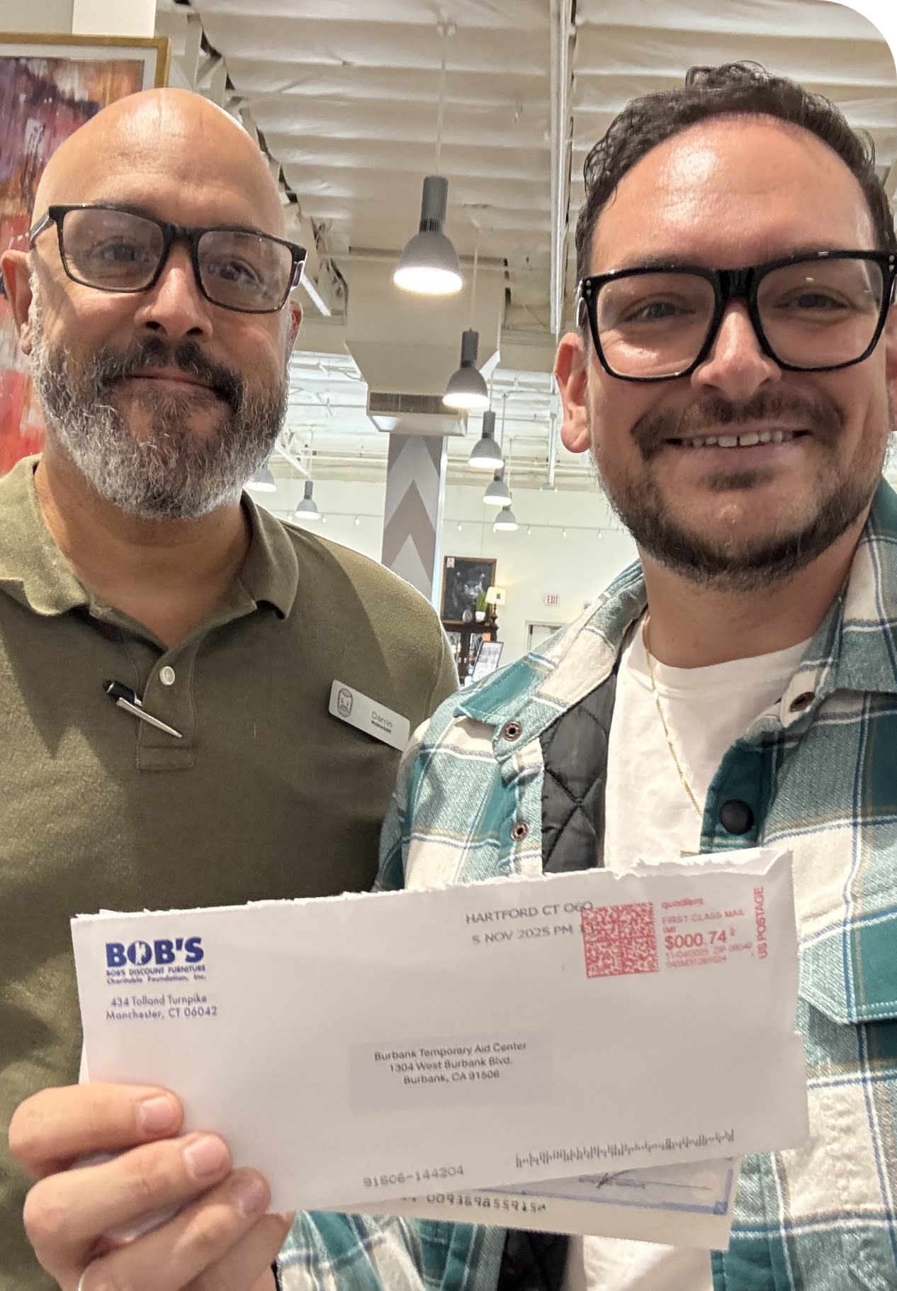 Two men holding an envelope from Bob's Discount Furniture.