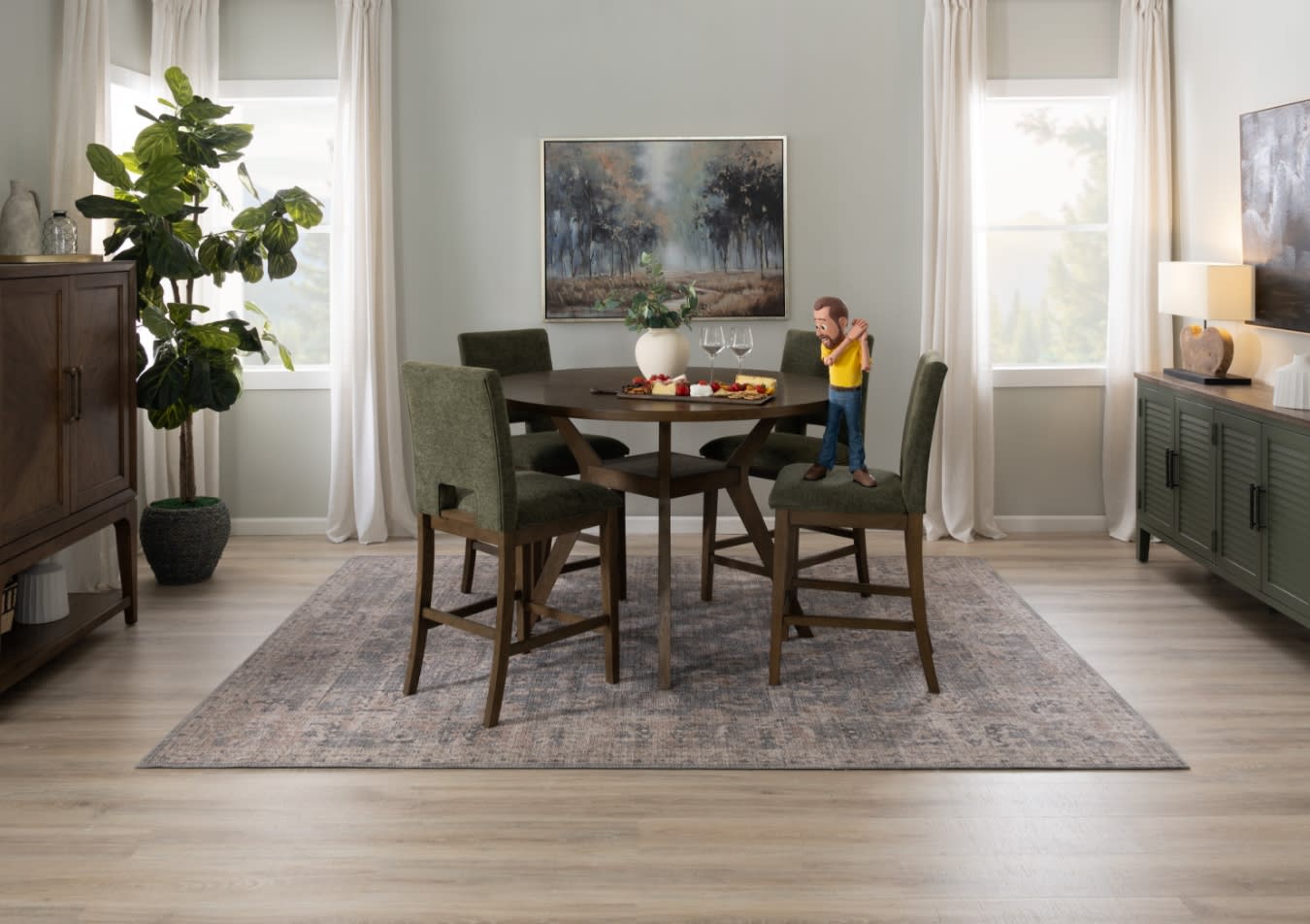 Dining room with a round dark wood table and four olive green upholstered chairs on a patterned area rug, featuring a decorative plant and snacks.