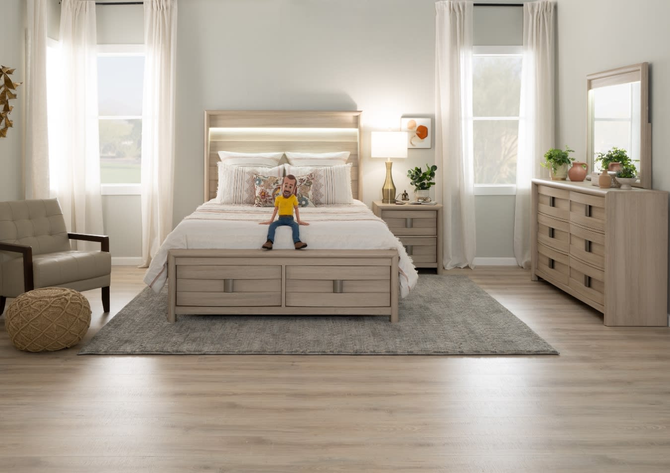 Modern bedroom with light wood furniture including a bed with storage drawers, matching nightstand and dresser, beige armchair, and neutral decor.