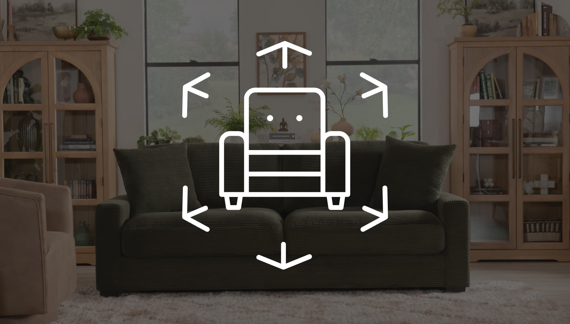 Dark green corduroy fabric sofa with two large cushions in a modern living room, overlaid with white line art of an armchair and directional arrows indicating 3D viewing or customization options.