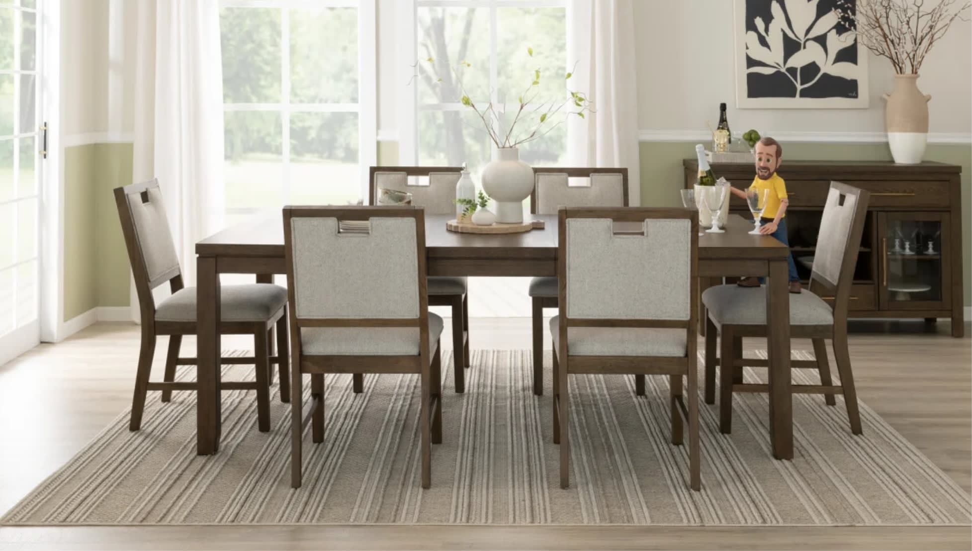 A modern dining room features a wooden table with six upholstered chairs on a striped rug. A vase with branches is centered on the table. A sideboard against the wall holds a wine bottle and glasses. A playful figurine is on the sideboard, adding a whimsical touch. Natural light streams through large windows, creating a serene atmosphere.
