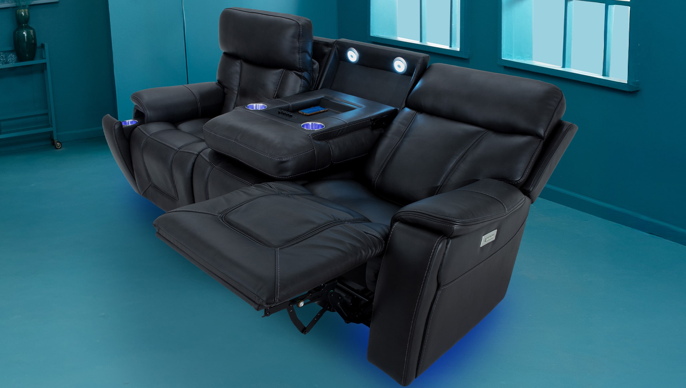 Black leather reclining home theater sofa with built-in cup holders, adjustable footrest, and center console with remote control storage.