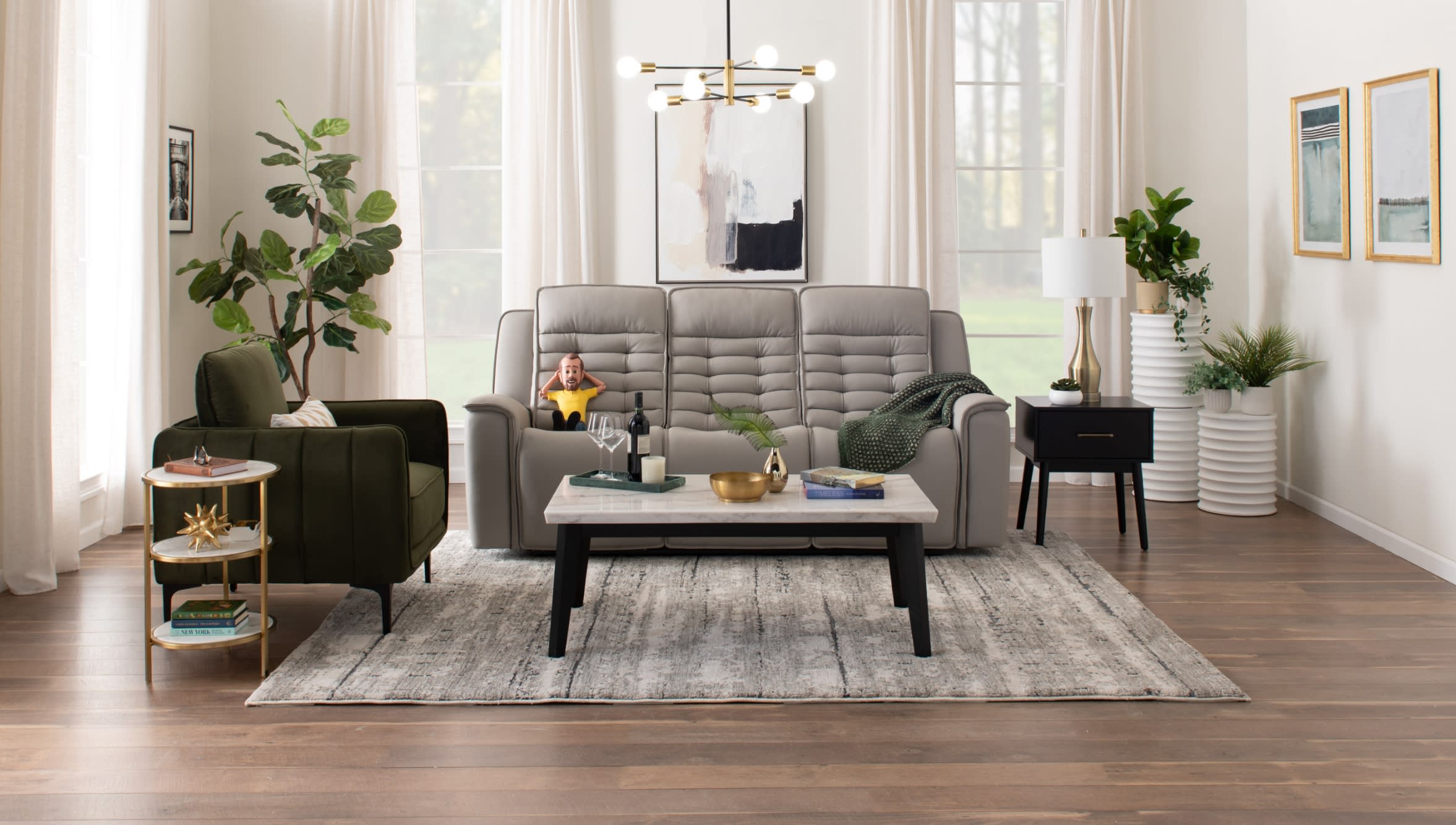 Modern living room with a gray leather tufted sofa, dark green velvet armchair, marble-top coffee table, black side table, and decorative plants.