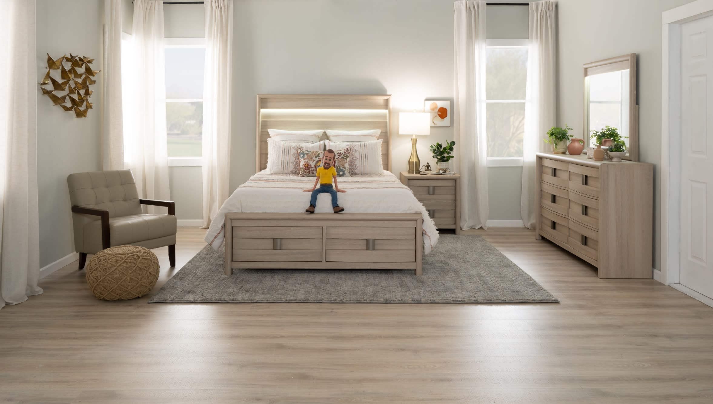 Modern bedroom with light wood platform bed, beige upholstered chair, matching dresser with mirror, neutral decor, and natural light from windows.