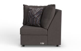 Dark gray fabric corner sofa section with plush cushions and a decorative geometric patterned throw pillow, featuring sturdy black legs and a metal connector plate.