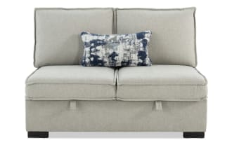 Playmax Gray Armless Storage Loveseat in gray polyester fabric with Bob-O-Pedic memory foam seating, hidden storage, and a blue patterned accent pillow.