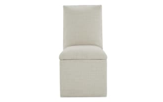 Beige upholstered armless accent chair with cushioned seat and backrest, featuring a textured fabric ideal for modern living spaces.