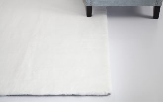 Long rectangular beige faux fur rug with a soft, plush texture, suitable for cozy home decor or bedroom use.