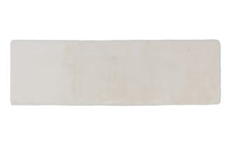 Long rectangular beige faux fur rug with a soft, plush texture, suitable for cozy home decor or bedroom use.